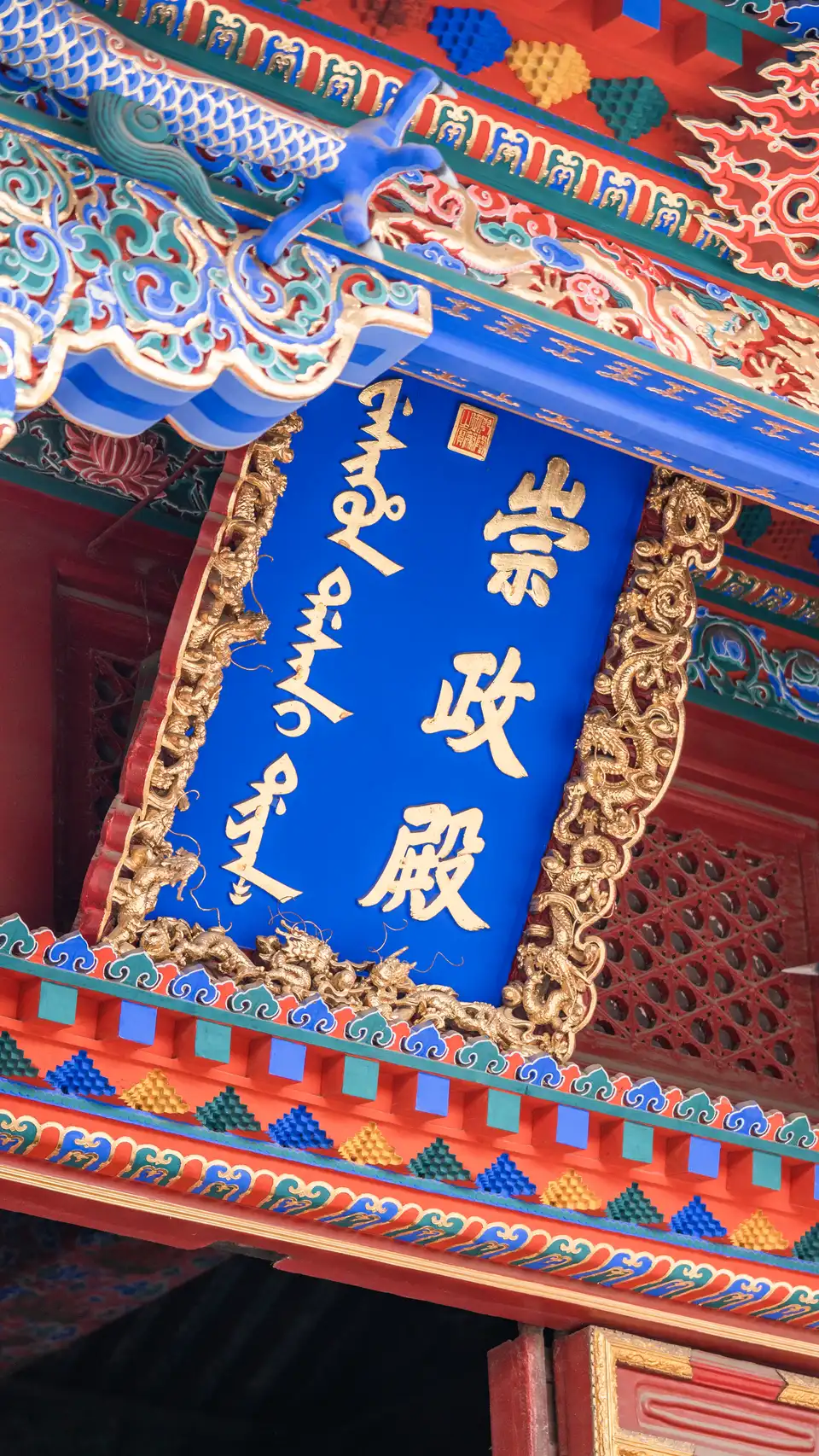 Close-up of a traditional Chinese architectural signboard and painted eaves with Chinese characters.